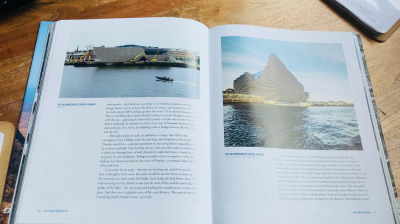 Open book with images and text about V&A Museum of Design in Dundee on wooden table.