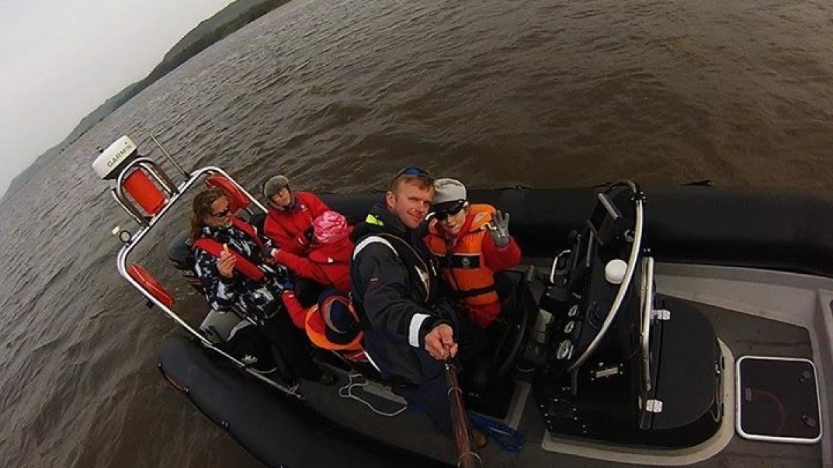 Group of people on a small boat taking a selfie on a lake or river.